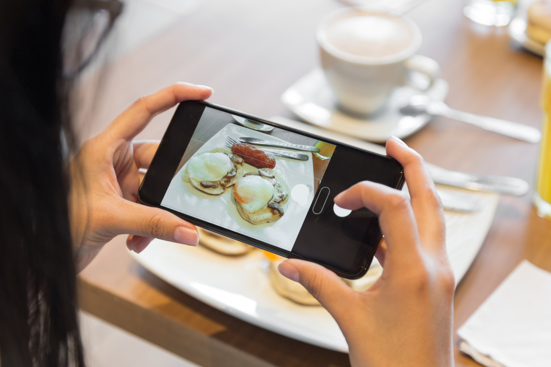 person taking a photo with cell phone at breakfast, photo in the day